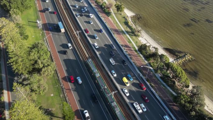 在阳光明媚的日子里，西澳大利亚珀斯市天鹅河旁的高速公路上的空中倾斜镜头