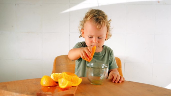 一个蹒跚学步的孩子榨了一片橘子汁，用他的小拳头捏了一下，然后喝了下去