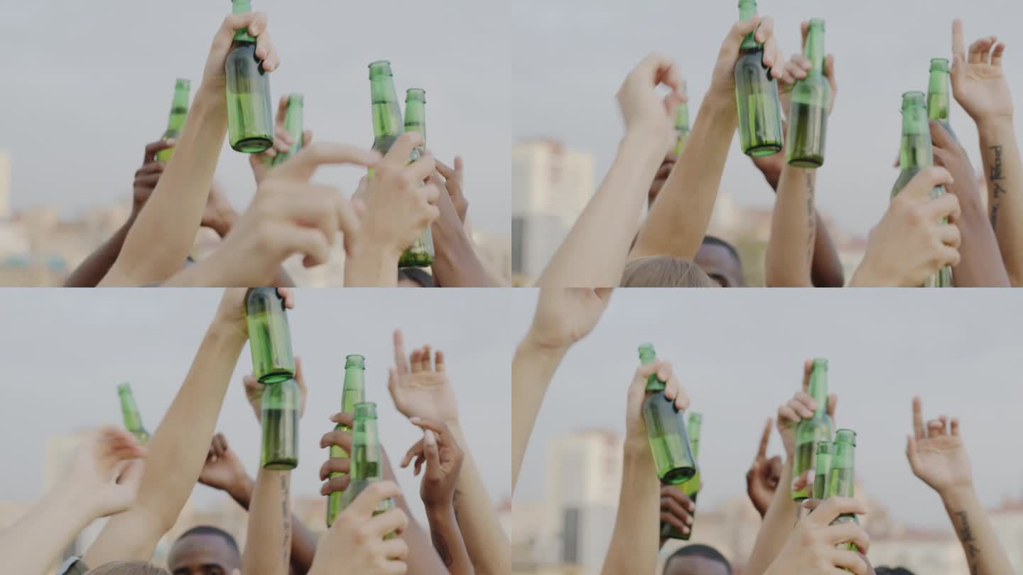 拿着啤酒瓶的手在天空的背景下跳舞的特写，而朋友们正在玩乐和喝酒