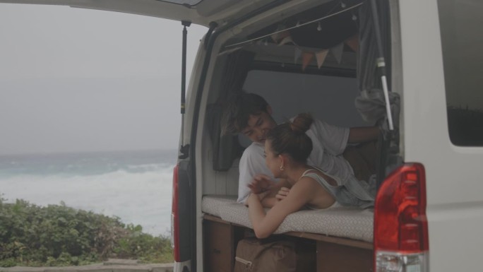一对幸福的日本夫妇躺在他们的面包车里聊天