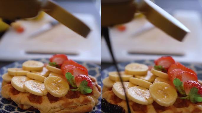 厨师将鲜奶油倒在香蕉和草莓的华夫饼上。早午餐的概念