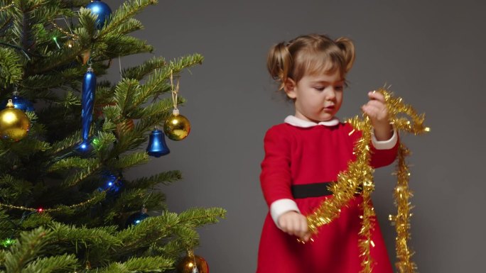 一个小女孩正在整理新年的金箔装饰圣诞树