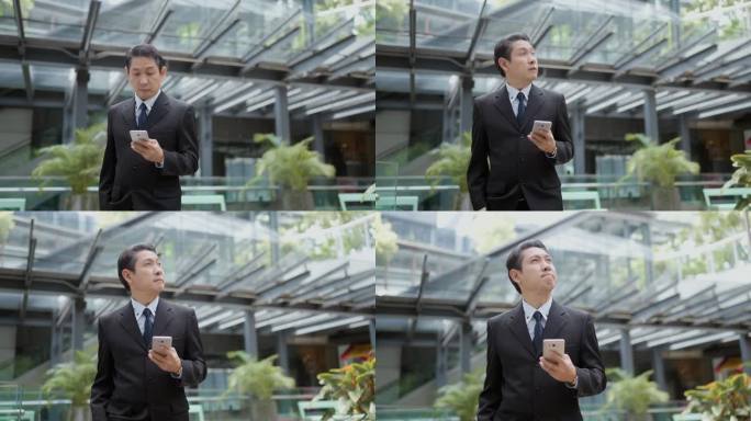 一位资深企业家走在一栋现代化的商业大楼里，一边用他的智能手机了解最新情况。