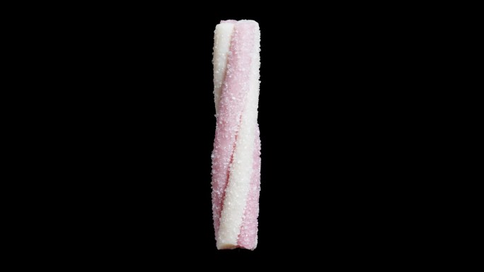 一种粘在一起的糖果，形状像一根扭曲的粉色棍子，上面撒满了糖。在一个特写镜头中，它在黑色的背景上旋转，