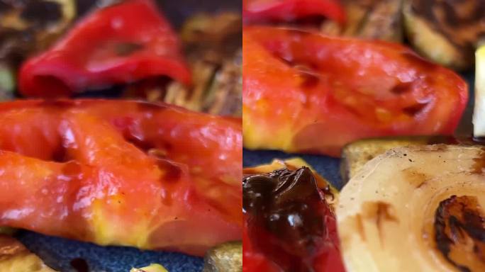 在浅灰色石板、石头或混凝土的背景上，盘子里烤着五颜六色的蔬菜甜椒、西葫芦、茄子。带复制空间的俯视图。