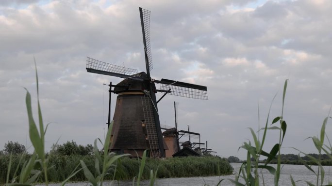 夕阳下的荷兰金德堤村美丽的木制风车。风车靠风运转。美丽的荷兰运河充满了水。美丽的日落。
