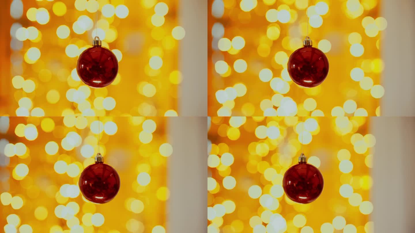 前景是一个红色的圣诞球，背景是闪烁的圣诞灯的美丽散景