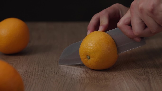 在木板上切橙子，黑背景