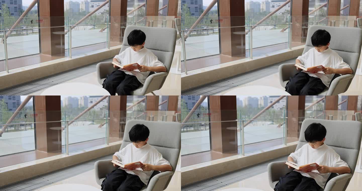 中国小男孩在图书馆大厅看书