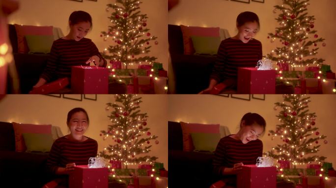 一名亚洲女子在圣诞夜打开礼盒时惊喜万分。