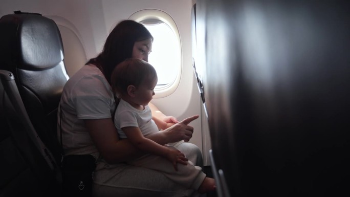 慈祥的妈妈在飞机上爱抚着蹒跚学步的小女孩