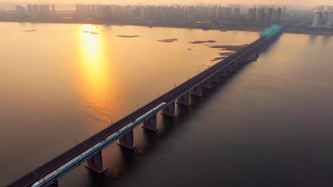 黄昏日落下的高铁穿过城市跨江大桥