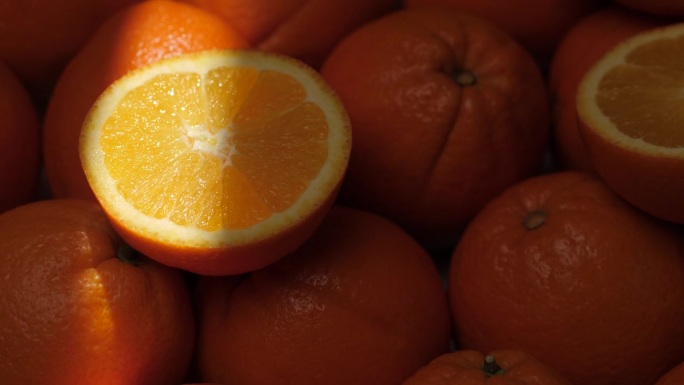 橙色水果。一束光照亮了阴影中切开的橘子。特写镜头
