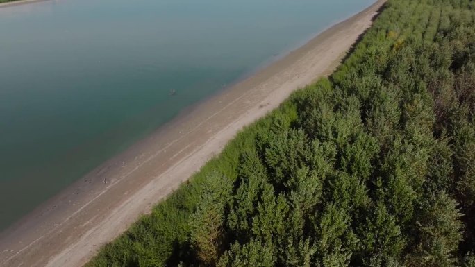 无人机在宁静的河岸和充满活力的绿色森林之间拍摄对角分割构图4K50fps电影级
