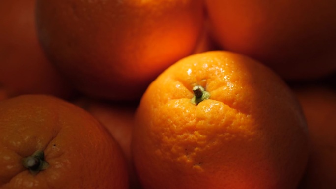 橙色水果。镜头慢慢向上移动，显示阴影中的橘子，阳光美丽地照在橘子上。特写镜头