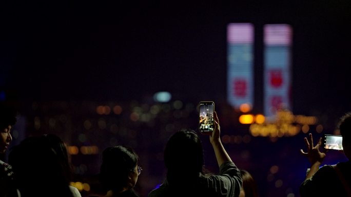 举起手机拍城市夜景的人背影