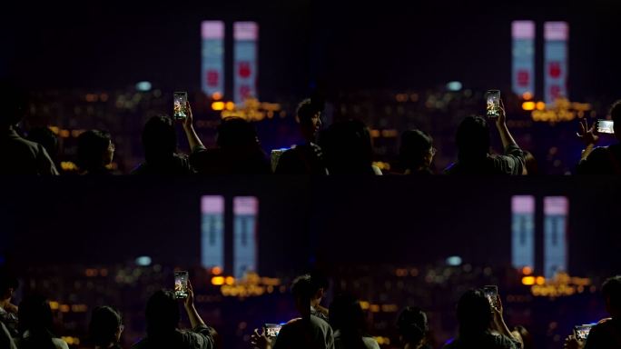举起手机拍城市夜景的人背影