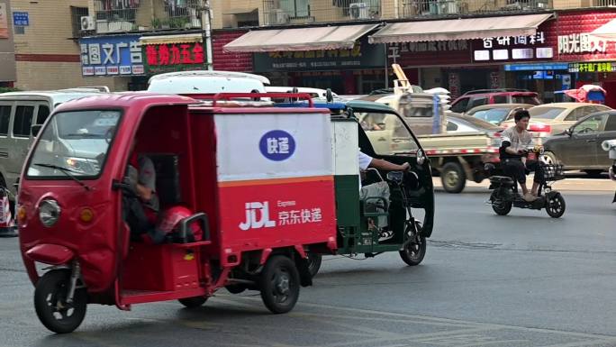 穿梭在十字路口的邮政快递车，京东快递车