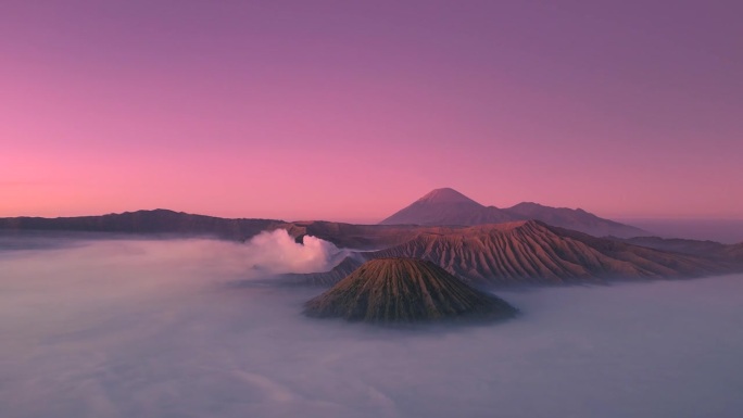 印尼东爪哇布罗莫腾格里塞默鲁国家公园，布罗莫火山上的日出和晨雾在下面蔓延。无人机鸟瞰图4K。