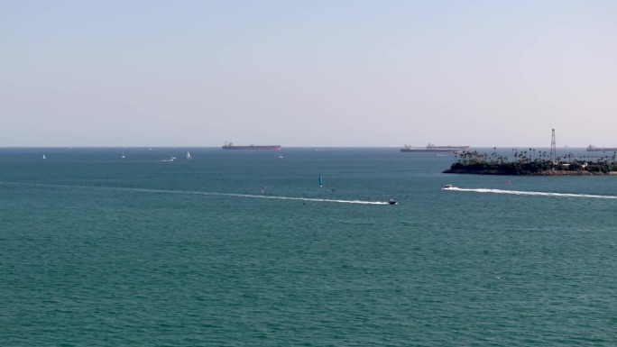 在加利福尼亚长滩海岸线上，风筝冲浪者的快艇巡航的空中跟踪拍摄