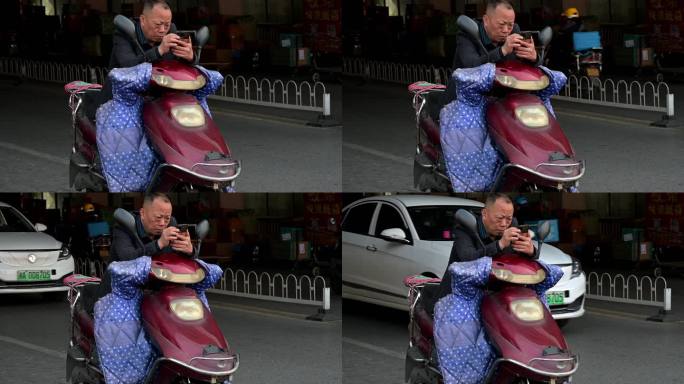 路口骑电动车的老年人使用智能手机