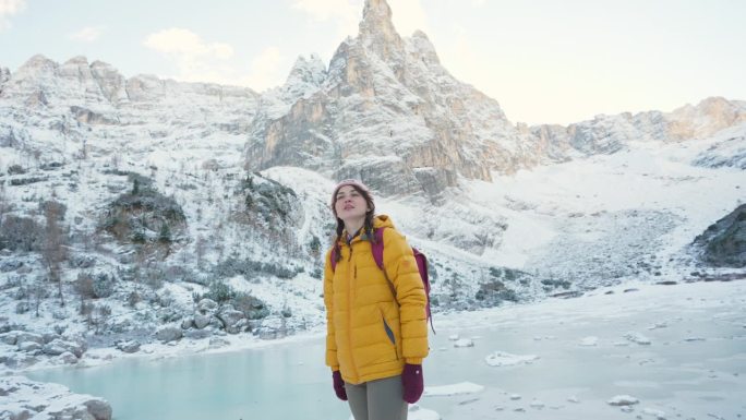 冬天，一名妇女在白云石的冰冻湖附近徒步旅行