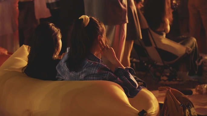 年轻女子坐在气垫沙发观看音乐节演出