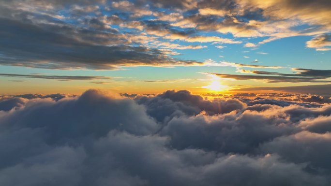 云中日出的空中超缩。清晨飞过浓密的云层。太阳给云顶涂上了暖橙色的光