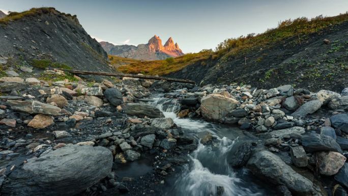 在法国萨瓦的秋天，法国阿尔卑斯山脉的Aiguilles d Arves山谷中标志性的三峰山和瀑布的景