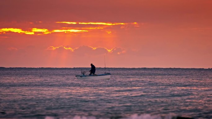 平静的海水渔民，新鲜的鱼在网和渔船的轮廓对日出天空的云与阳光射线视频