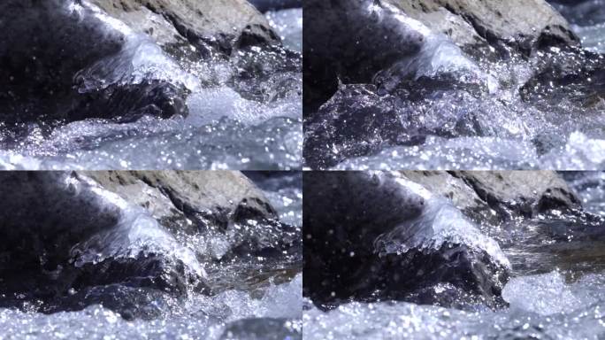 湍急的流水冲过冰凌岩石 流水拍打岸边黑石