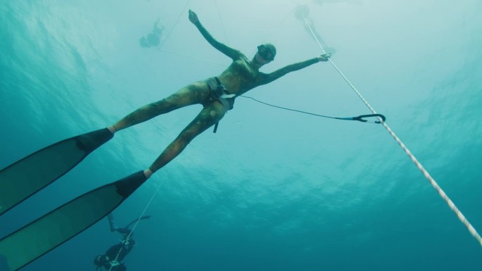 在海上的绳索上自由潜水。女自由跳水运动员在热身潜水时挂在绳子上，训练静态屏气