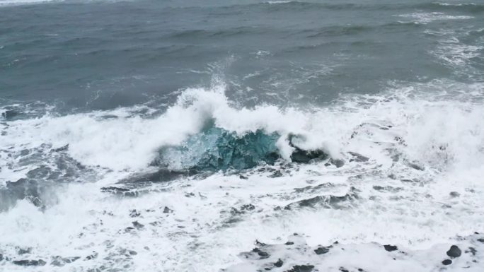 令人惊叹的无人机拍摄的波浪在冰岛钻石海滩美丽的冰岩上破碎(慢动作)