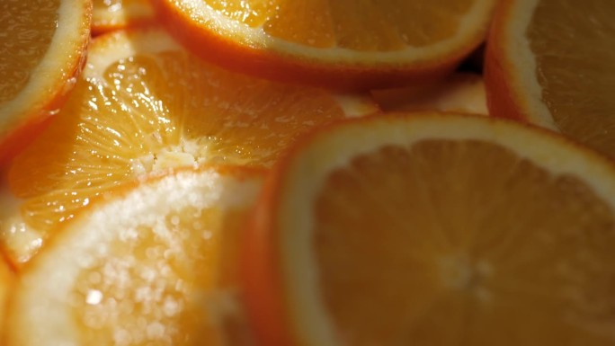 橙色水果。微距镜头缓慢移动，显示阴影中切片的新鲜多汁橙子，橙子被阳光照射