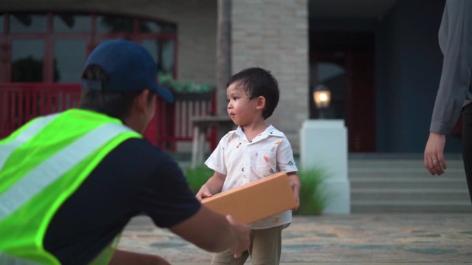 小男孩和他的妈妈从家门口好心的快递员手里接过一个包裹，心情愉快。