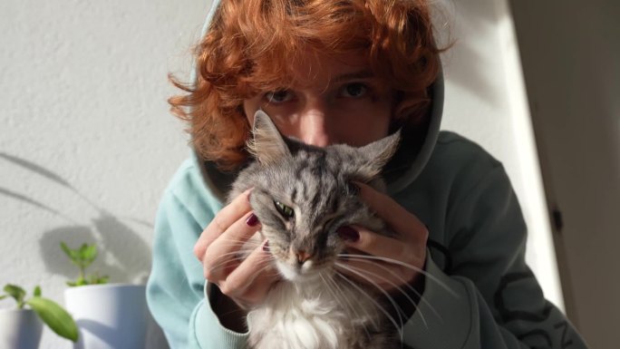 十几岁的红发女孩和毛茸茸的绿眼睛猫的肖像