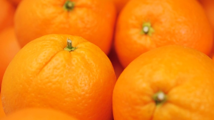 橙色水果。镜头缓缓向上移动，呈现新鲜橙子的特写