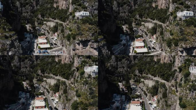 无人机穿过意大利陡峭山脉的照片显示，房屋建在陡峭的斜坡上。