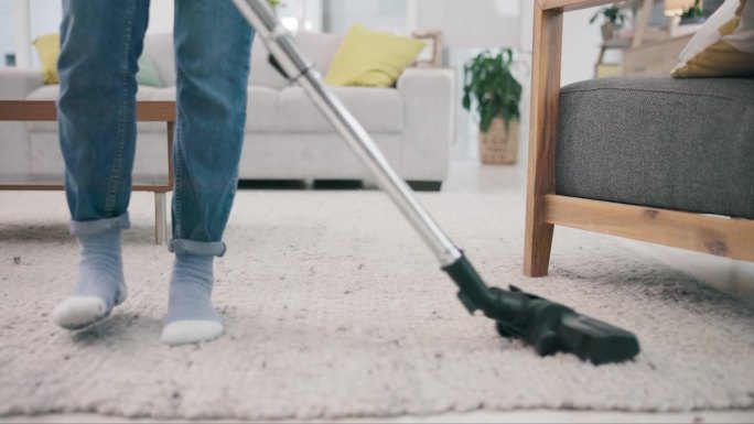 脚，地毯和吸尘器在家里春季大扫除与一个人在客厅的特写。一个成年人在公寓里做家务或家务的地板、器具和设