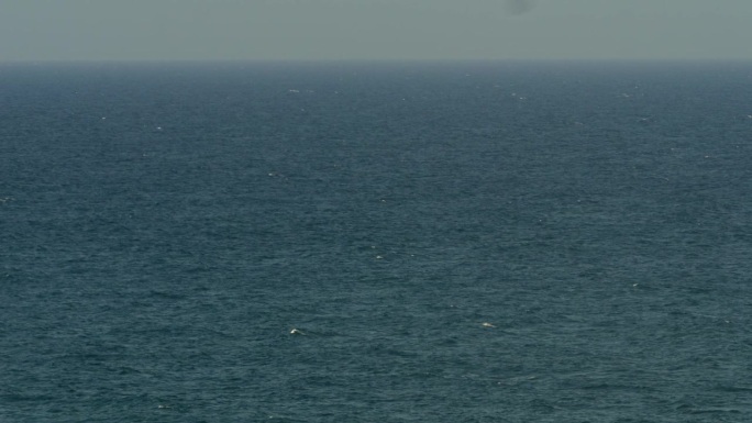 鸟瞰图的海面，波浪延伸到地平线上的一个轻微的波涛汹涌的海上由于风，空气中的高湿度。