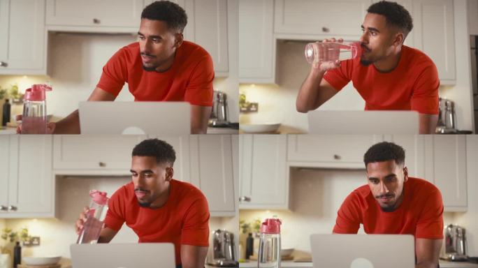 一名男子穿着健身服在家里的厨房里用笔记本电脑喝水