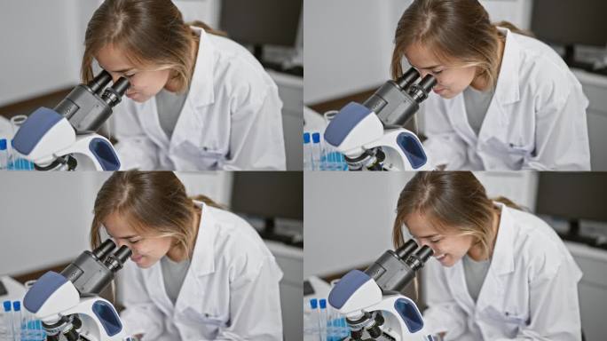 年轻，乐观的金发科学家在工作，带着自信的微笑和显微镜在实验室里发现科学的奇迹