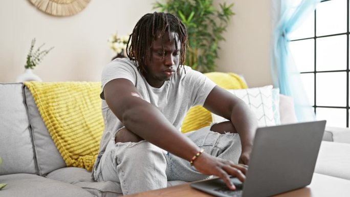 非裔美国人躺在沙发上合上笔记本电脑，用靠垫盖住脸