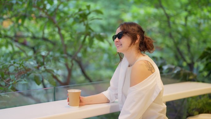 戴墨镜的女人在咖啡馆喝咖啡的画像