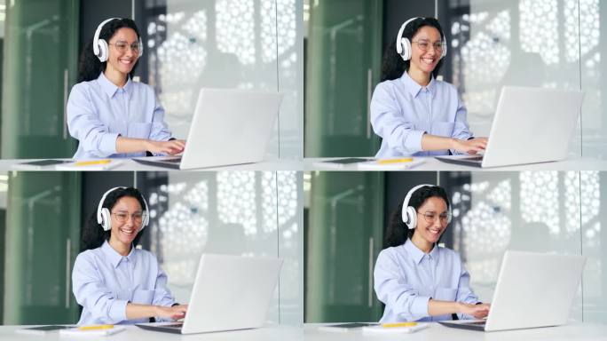 年轻快乐的女员工，戴着耳机在笔记本电脑上打字，坐在办公桌前。