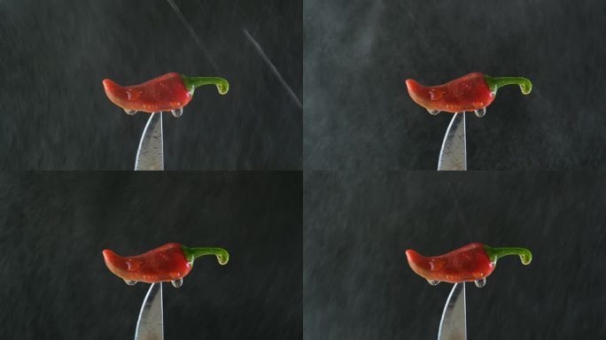一把滴着水的刀上放着一个红辣椒