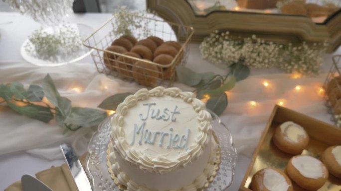 一张甜点桌，上面放着写着新婚的婚礼蛋糕。