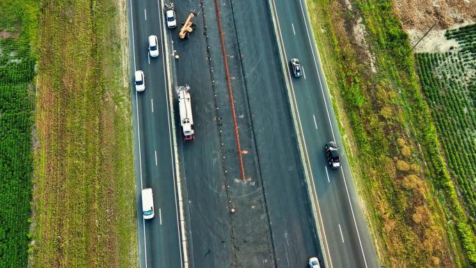在北卡罗来纳州的绿地中，水泥搅拌机和反铲挖掘机在高速公路拓宽工程中工作。航拍镜头与向后倾斜向上的相机