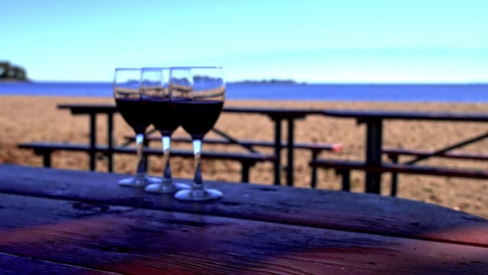 汉德从海滩外面的桌子上拿起盛酒的玻璃杯，慢镜头