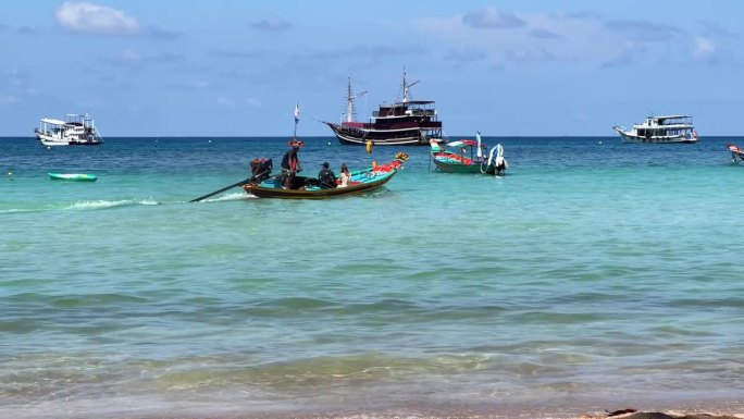 泰国长尾摩托艇从岸边驶出，在碧绿的海水中驶向大海
